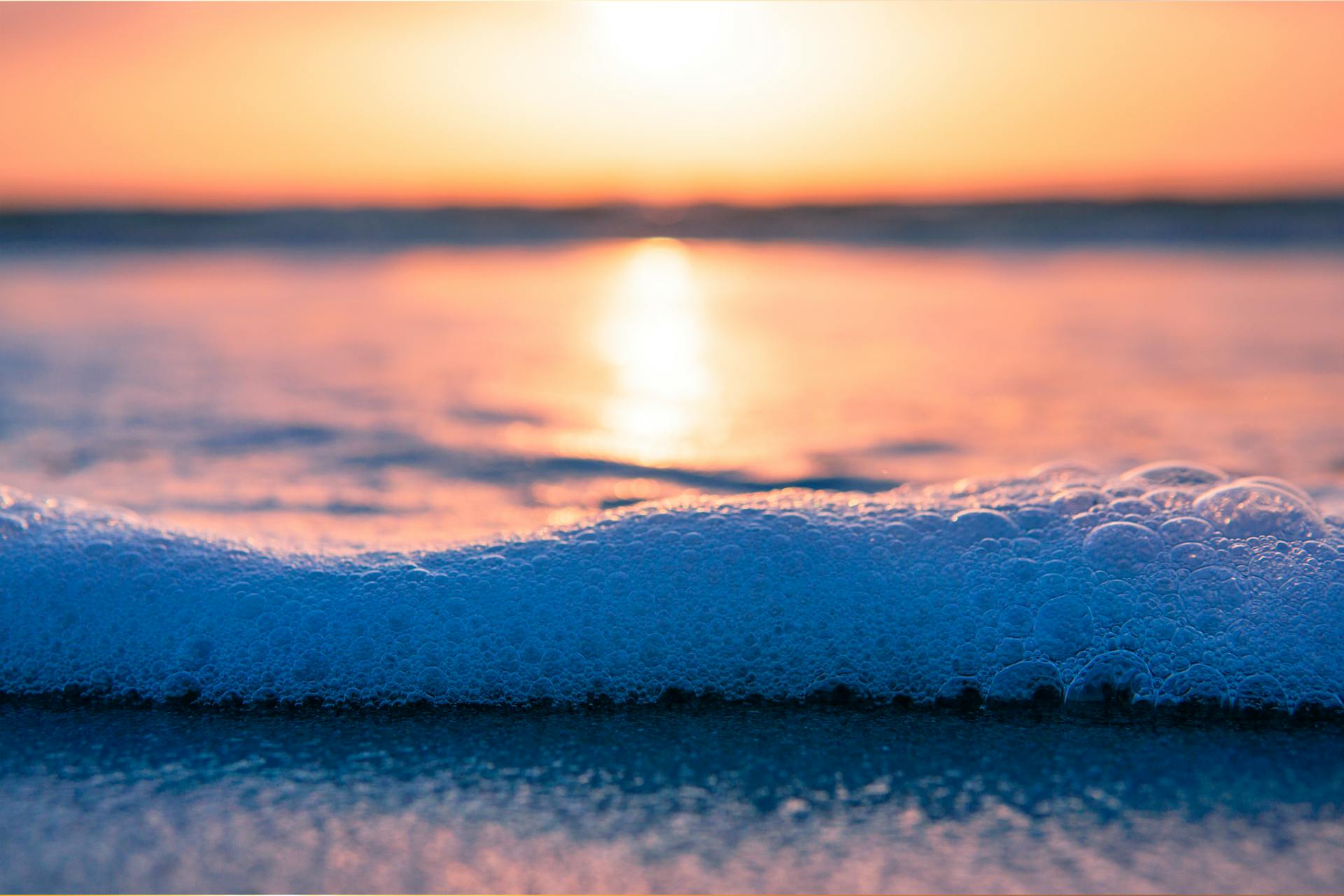 Peaceful sunrise at Cocoa Beach with gentle ocean foam and vibrant skies.