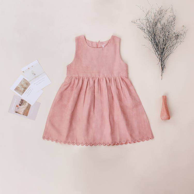 Trendy dress for girl near postcards on beige background