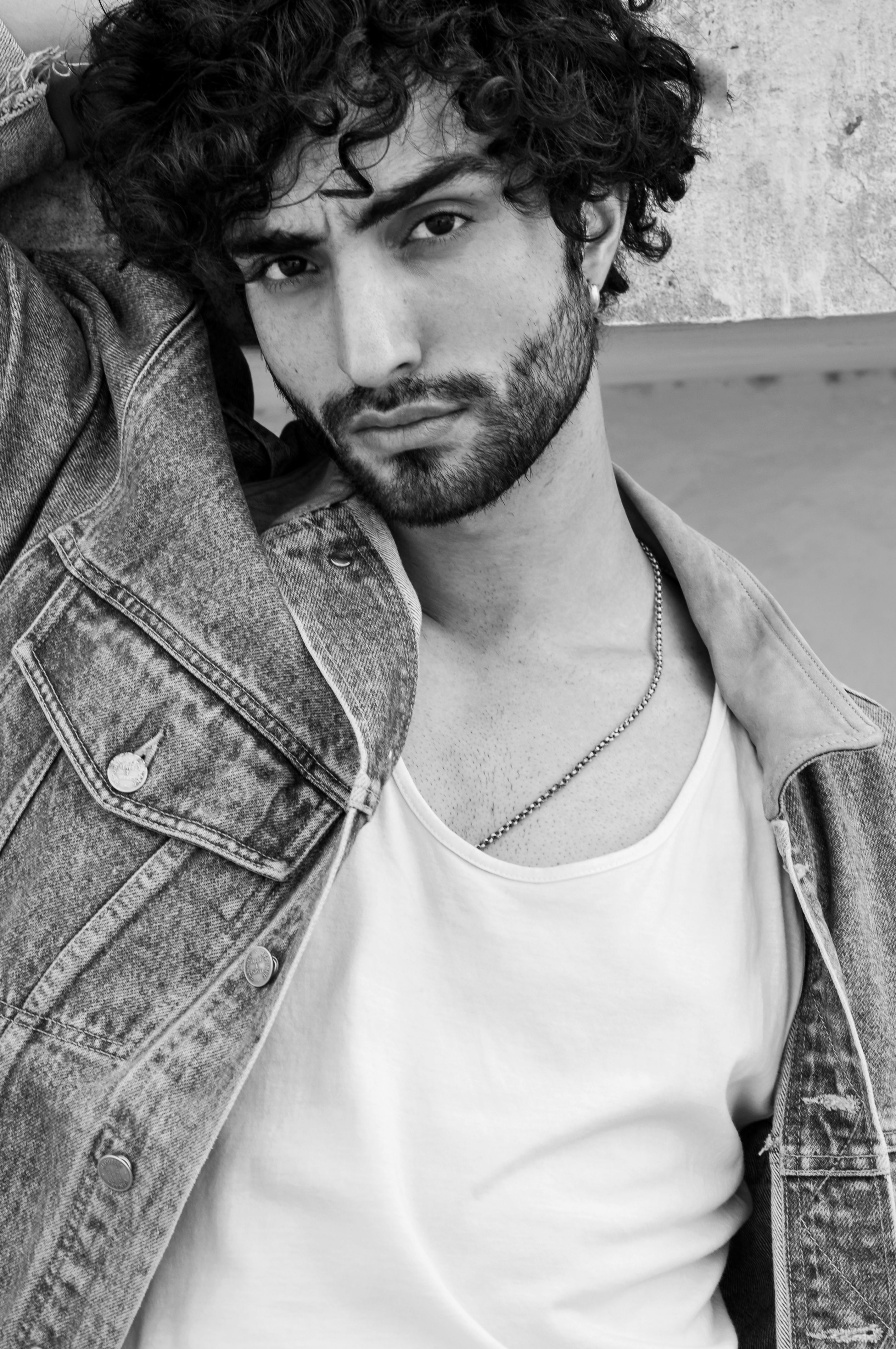 Stylish black and white portrait of a man with a beard wearing a denim jacket and white shirt.