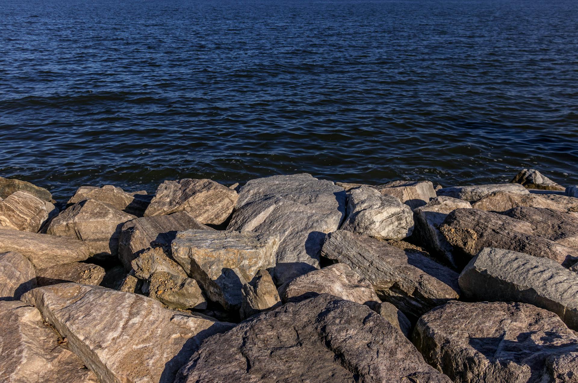 Enjoy the tranquility of a rocky shoreline along the Maryland coast with clear blue water.