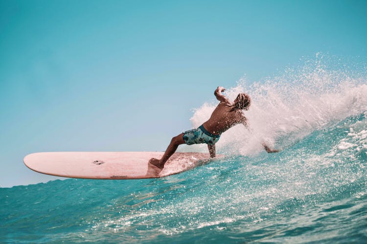 Sporty Shirtless Guy Balancing On Surfboard In Ocean