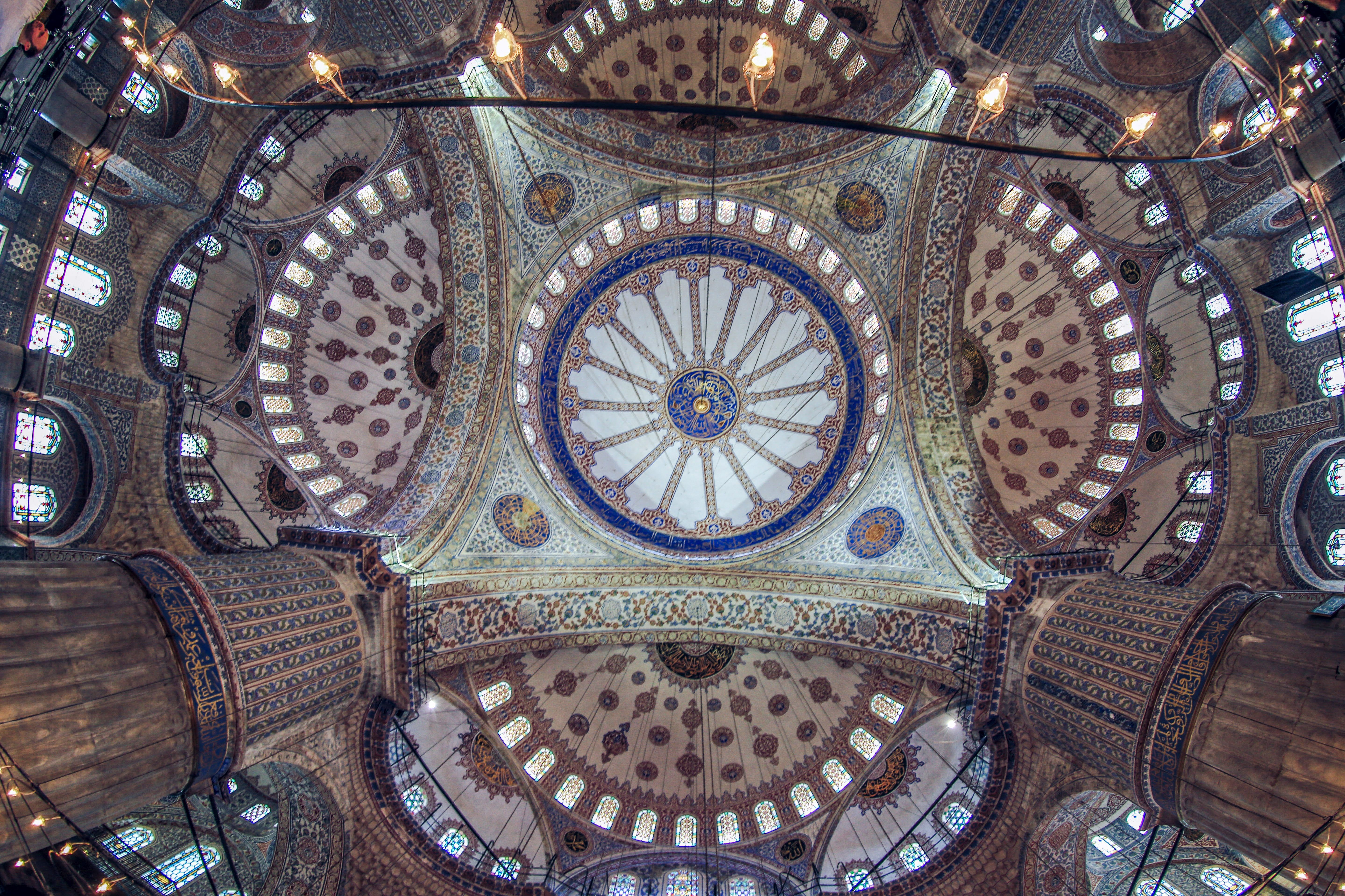 Interior luxuoso do Four Seasons Istanbul at Sultanahmet com teto ornamental e janelas arqueadas.