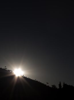 Silhouetted mountain landscape with sunrise, capturing the glowing light and serene beauty of dawn.