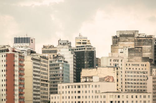 Free Multistory residential apartment houses with shabby walls located close to each other on city street against gray sky in district Stock Photo