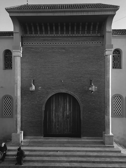 A Grayscale Photo of People Sitting in Front of the Building