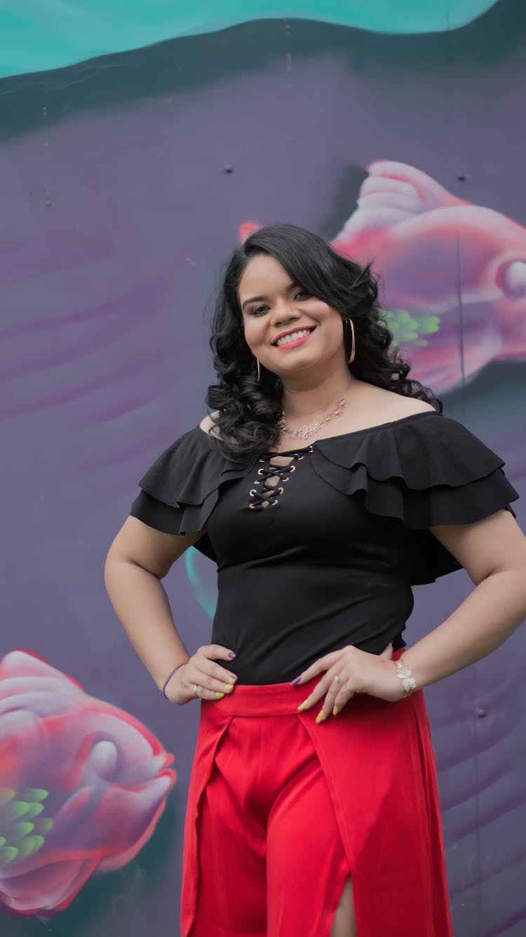 A Woman In Black Shirt And Red Skirt Posing With Hands On Waist