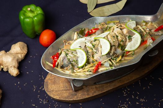 A beautifully presented steamed fish with lime, herbs, and spices, showcasing vibrant food textures.