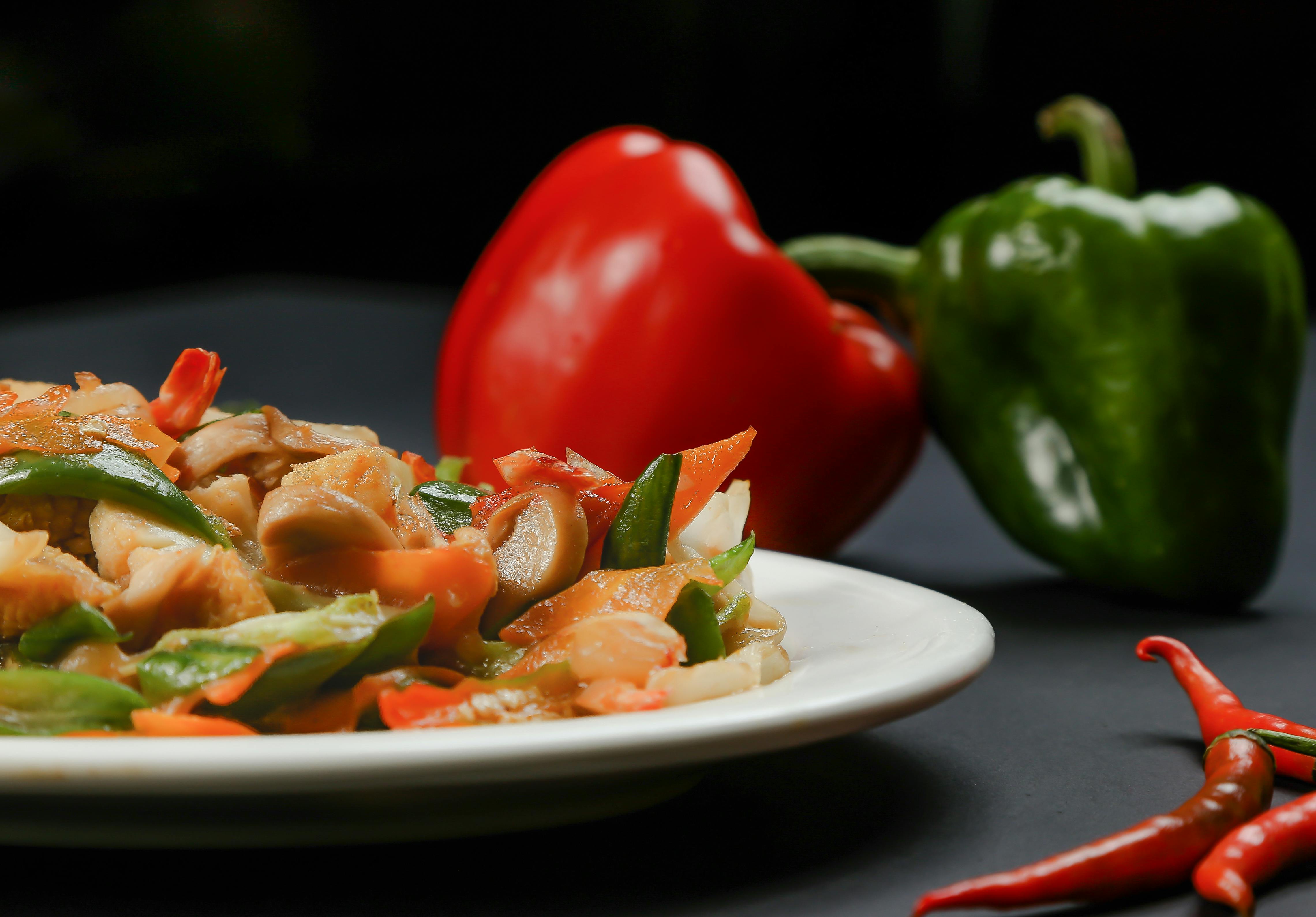 A vibrant stir fry with bell peppers on a white plate, showcasing delicious food photography.