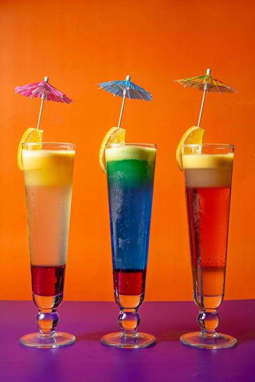 Colored Cocktail Drinks with Slices of Lemons and Paper Umbrellas