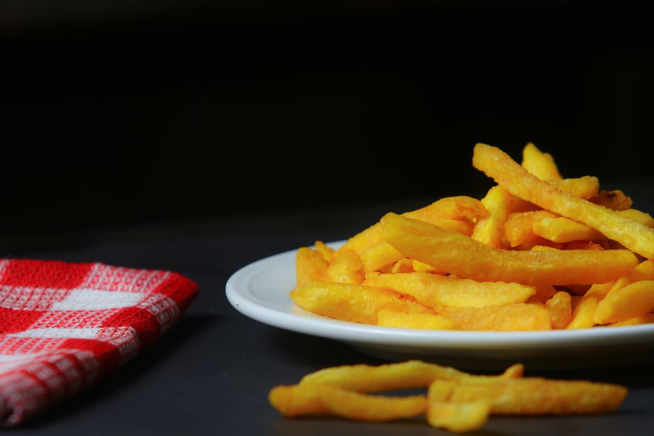 Close-up of crispy French fries on a plate with a red checkered napkin.