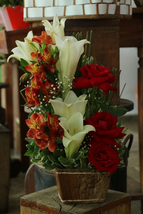 Free Delicate floral arrangement with lilies and roses in a wooden pot indoors. Stock Photo