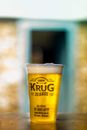 Plastic glass of fresh beer with frothy foam on top placed on table in outdoor cafe