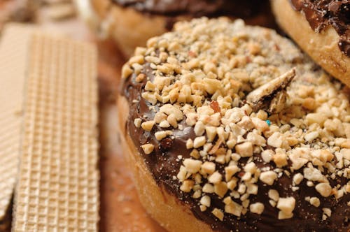 Free High angle sweet donut topped with chocolate frosting and chopped nuts placed near waffles on board Stock Photo