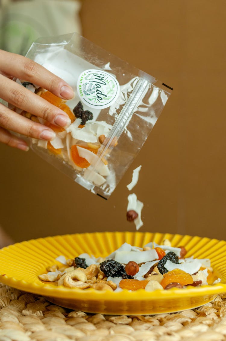 Woman Pouring Dried Fruit Into Plate