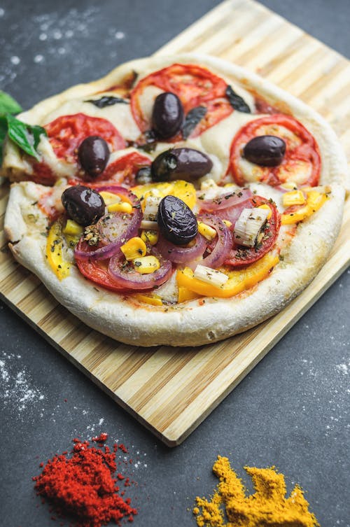 Free From above of pizza served on wooden board with stripes near bright condiment Stock Photo