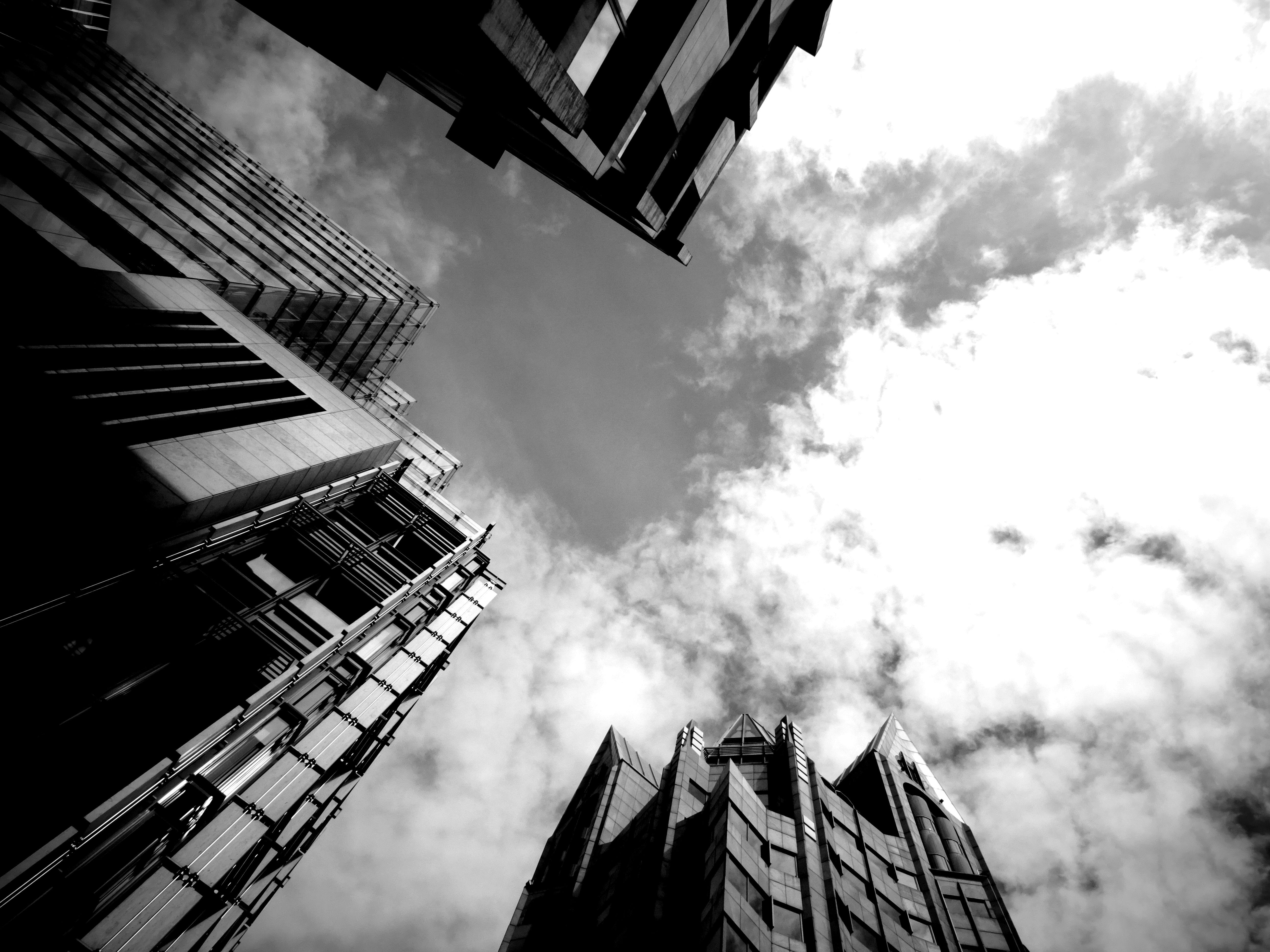 低角度视角下单色描绘的摩天大楼高耸于多云天空下，展现城市建筑风貌