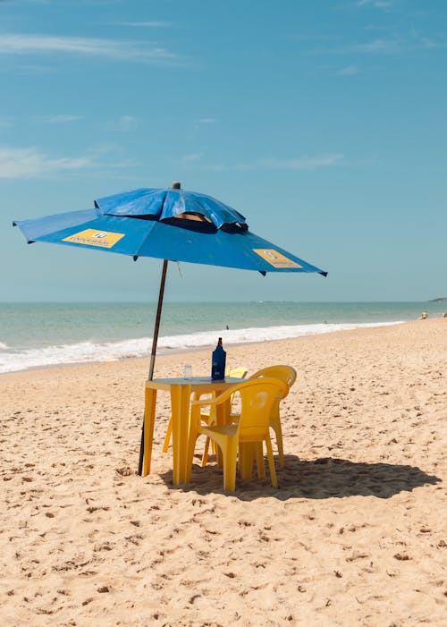 Free Table and chairs under umbrella on sandy beach Stock Photo