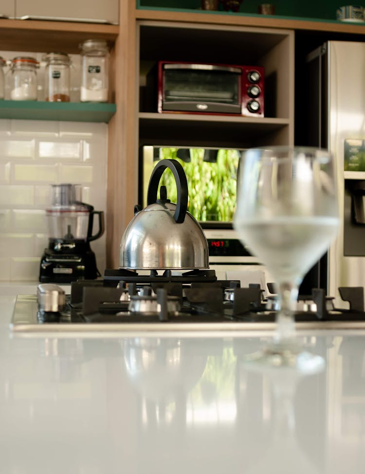 Water Glass Placed On Counter Near Stove With Pot In Stylish Kitchen