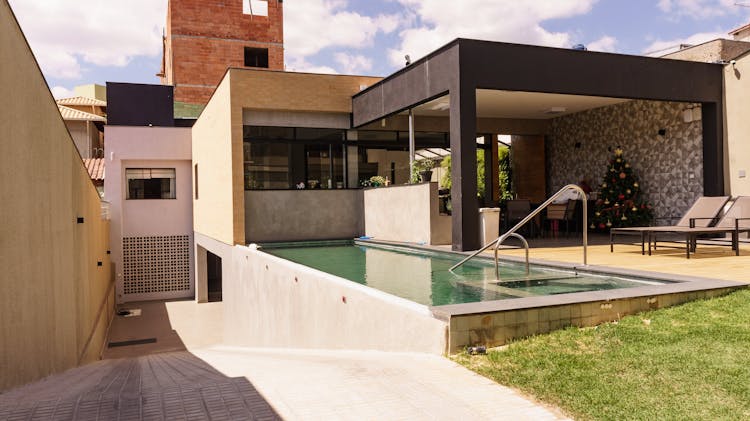 Pool And Sun Loungers In Backyard Of Contemporary House