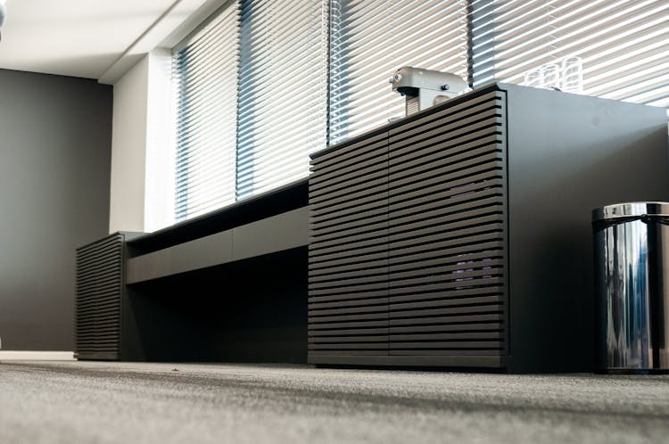 Table With Coffee Machine Near Trash Can In Modern Workspace