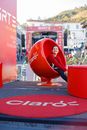 Happy young female wearing casual clothes sitting in red plastic egg chair placed on street during outdoors exhibition