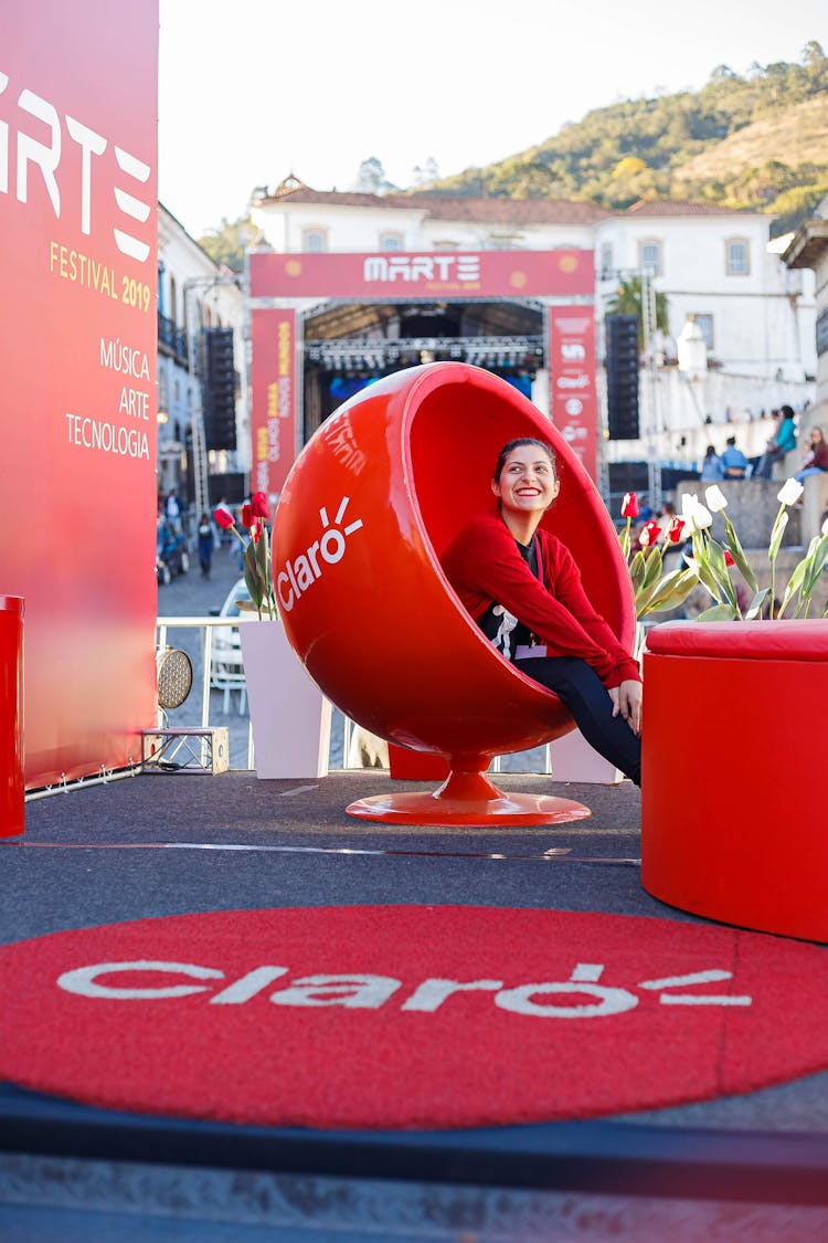 Cheerful Woman Sitting In Egg Chair On Street