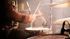 Side view crop anonymous male musician playing drums during live concert on concert stage