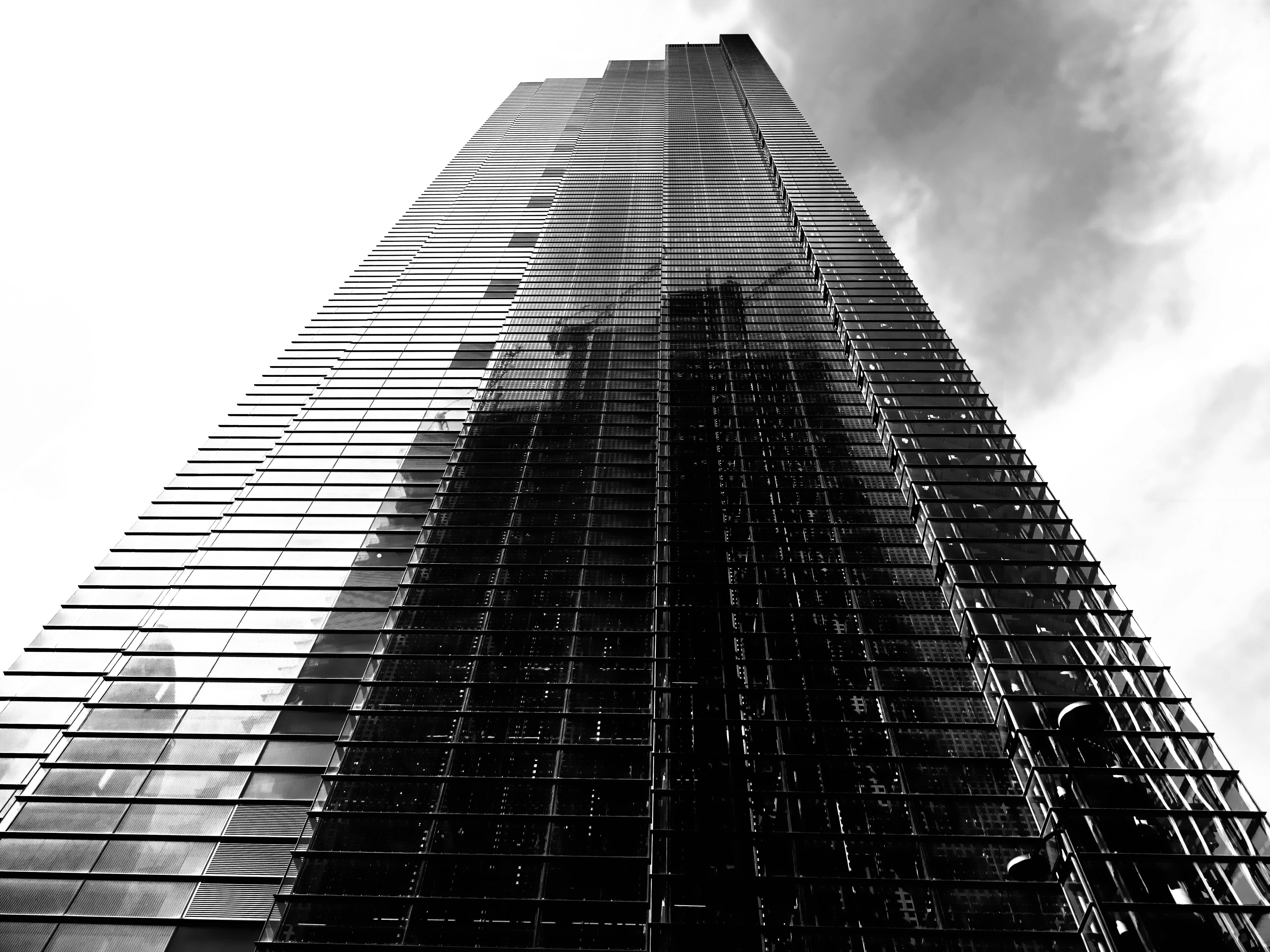 黑白低角镜头下的现代摩天大楼反射着多云的天空