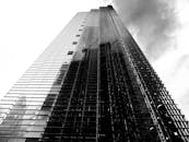 黑白低角镜头下的现代摩天大楼反射着多云的天空