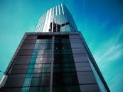 低角度视角下的现代摩天大楼，反光玻璃立面映衬着晴朗的天空