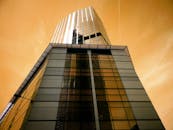 现代摩天大楼的玻璃立面反射着天空，从低角度看去，营造出未来派城市景观