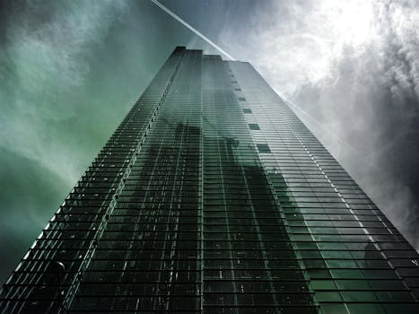 现代摩天大楼以低角度呈现，反光玻璃窗映照着多云的天空，格外引人注目