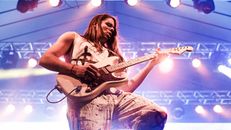 From below professional focused male musician playing electric guitar under soffit lights during rock concert