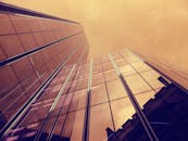 从低角度仰望现代玻璃摩天大楼，映照出温暖黄昏天空的景象令人惊叹