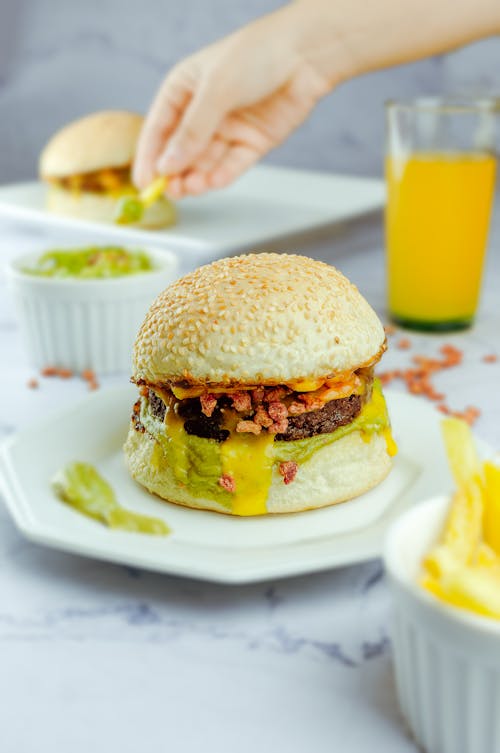 Free Appetizing hamburger on plate among sauce and orange juice Stock Photo
