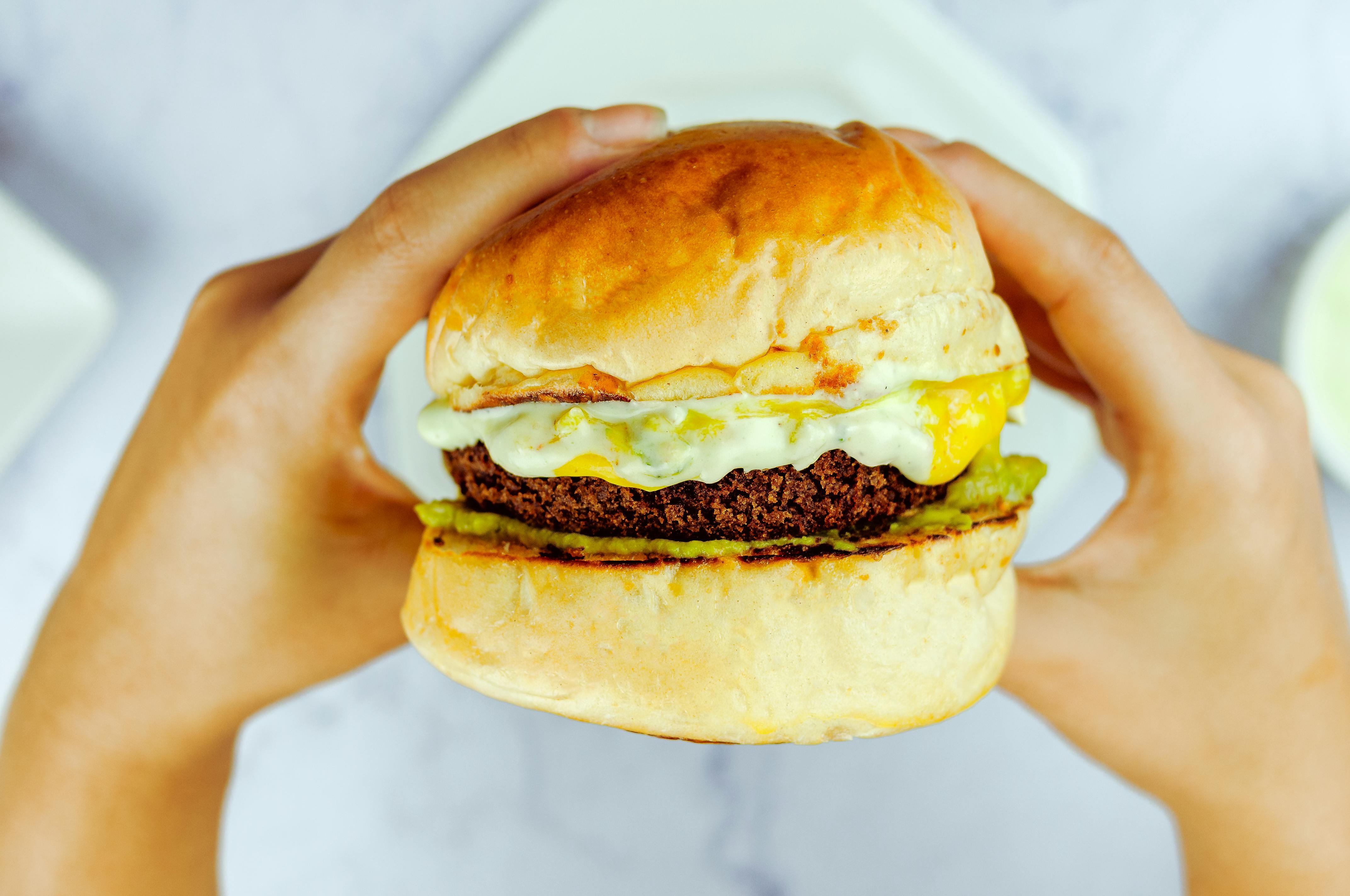 unrecognizable person eating burger in daytime