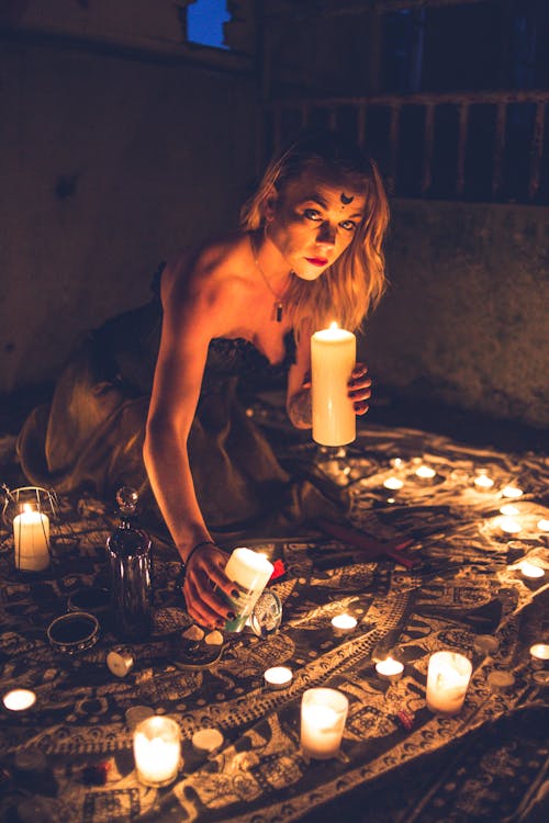 Mysterious woman among candles during dark ritual