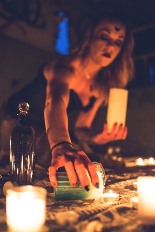 Free Ground level of woman burning many candles while preparing for magical prayer in dark Stock Photo
