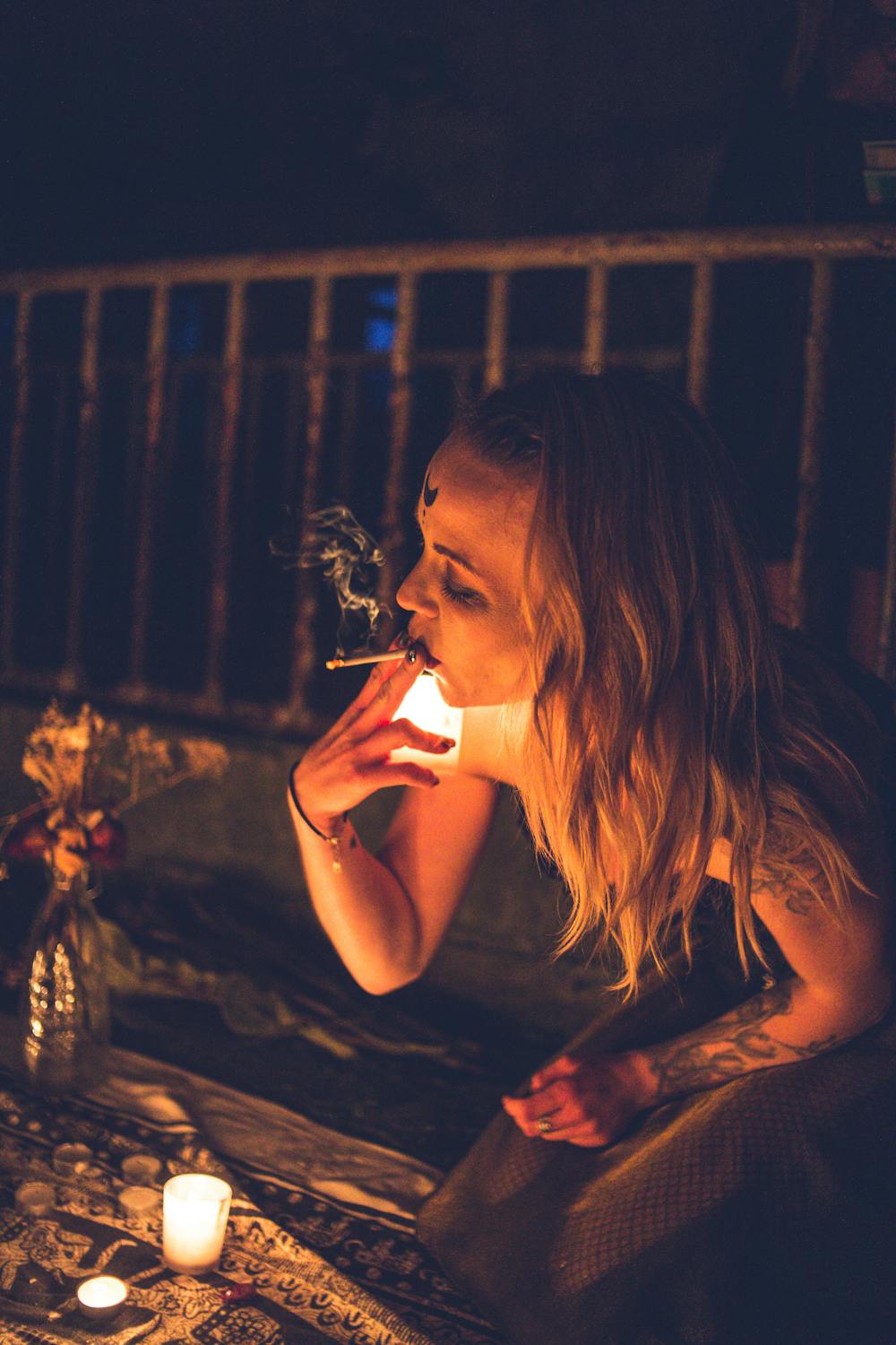 Woman smoking among candles in night · Free Stock Photo