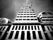 一张低角度拍摄的现代摩天大楼黑白照片，展现了玻璃窗和建筑细节