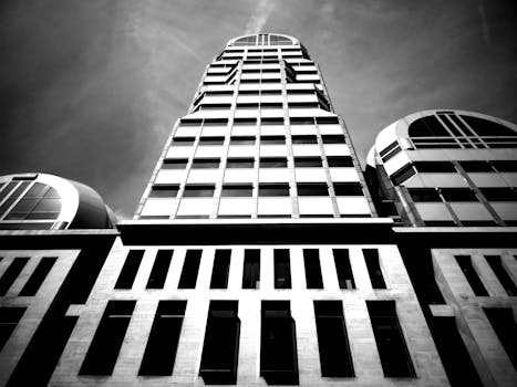 一张低角度拍摄的现代摩天大楼黑白照片，展现了玻璃窗和建筑细节