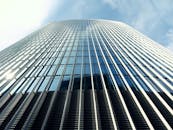 现代摩天大楼的玻璃立面反射出清澈的蓝天，从低角度欣赏尤为美丽