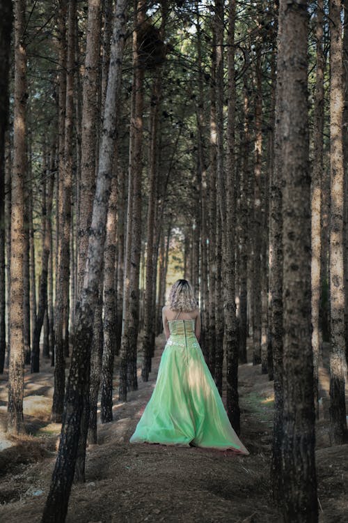 Back View of a Woman in Green Long Dress Standing in the Woods