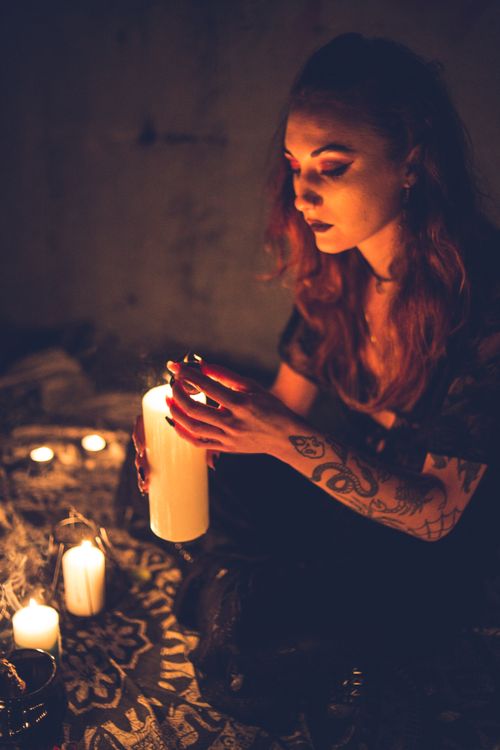 Free Calm mysterious woman with tattooed arm holding bright burning candle in dark Stock Photo