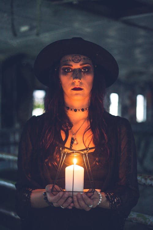 Emotionless sorceress with candle in dark