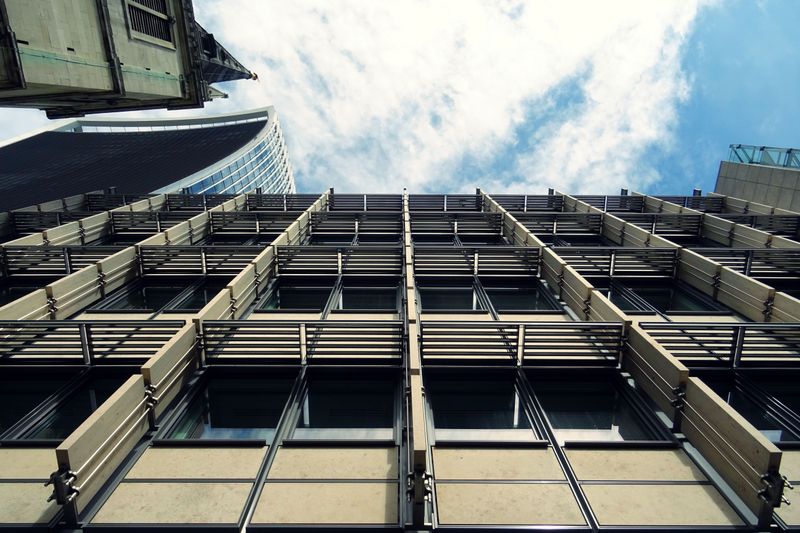 Low-angle view of a modern urban skyscraper with glass windows and abstract architectural design.
