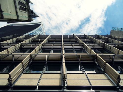 Free Low-angle view of a modern urban skyscraper with glass windows and abstract architectural design. Stock Photo