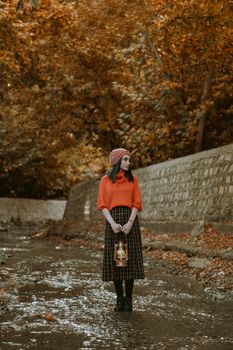 一位穿着充满活力秋季服装的女人在公园小道上提着灯笼