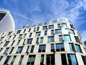 低角度镜头下的现代摩天大楼，玻璃立面映照着蓝天