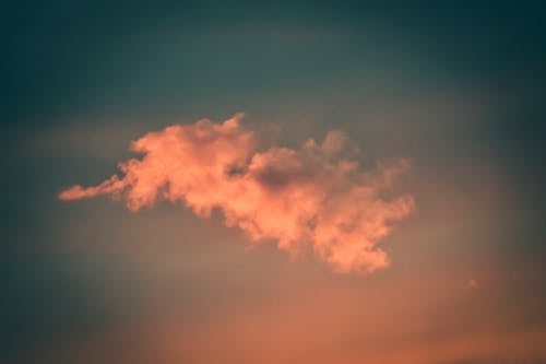 Free From below of fluffy bright orange cloud floating in picturesque colorful sunset sky Stock Photo